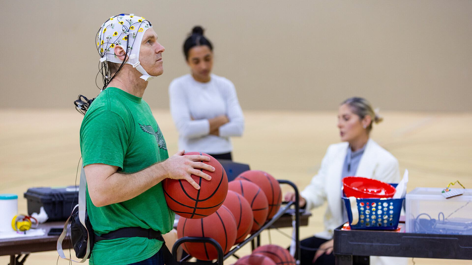 man with EEG cap prepares to shoot basketball