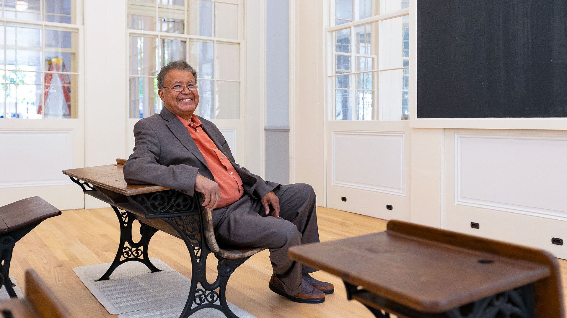 man sits on bench in old-fashioned classroom