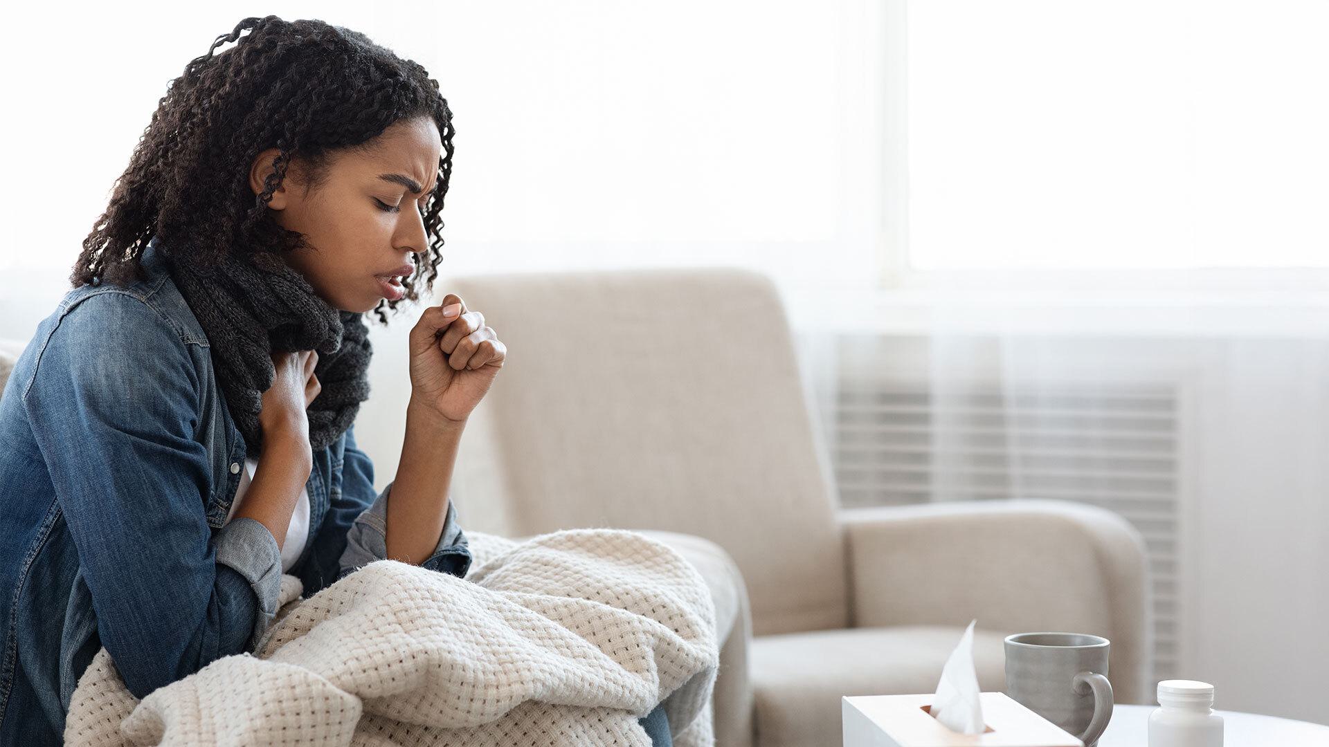 woman holds chest and coughs