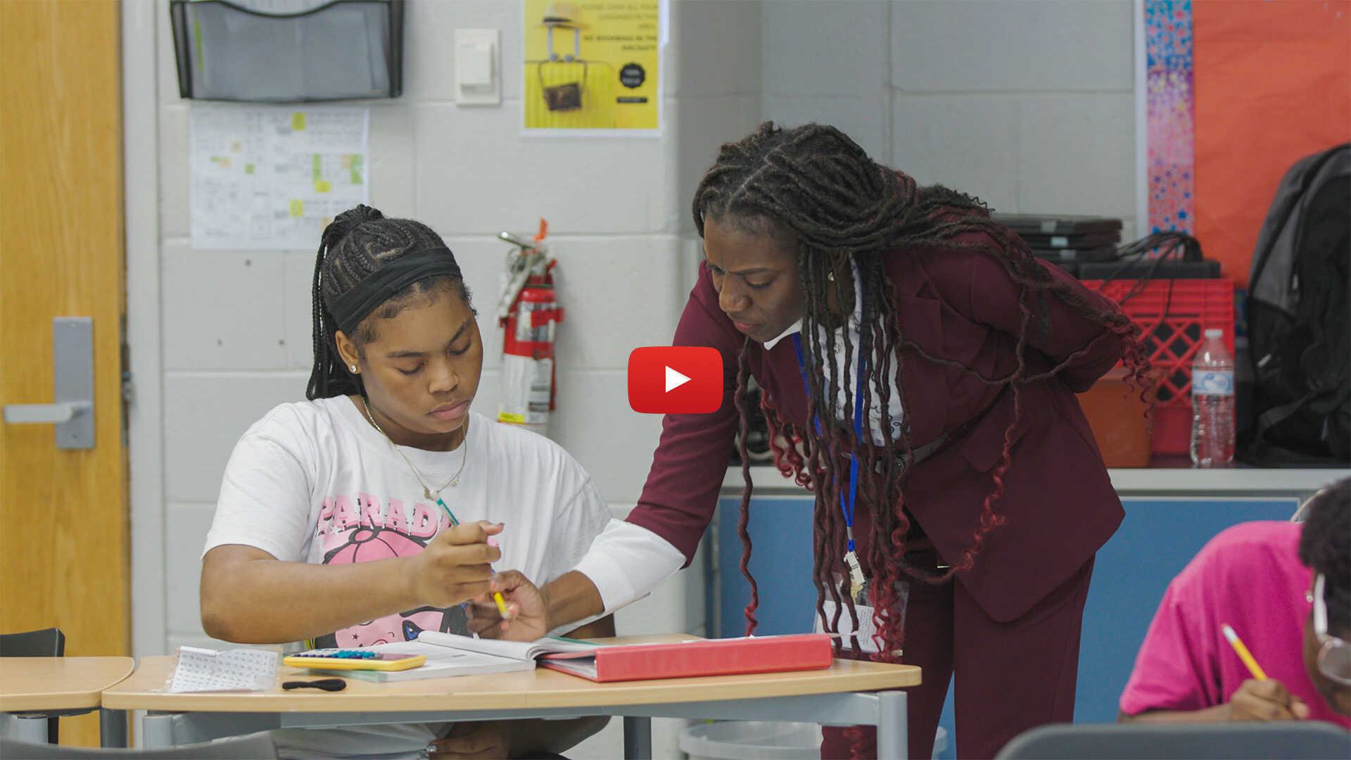 teacher works with student, with red play button