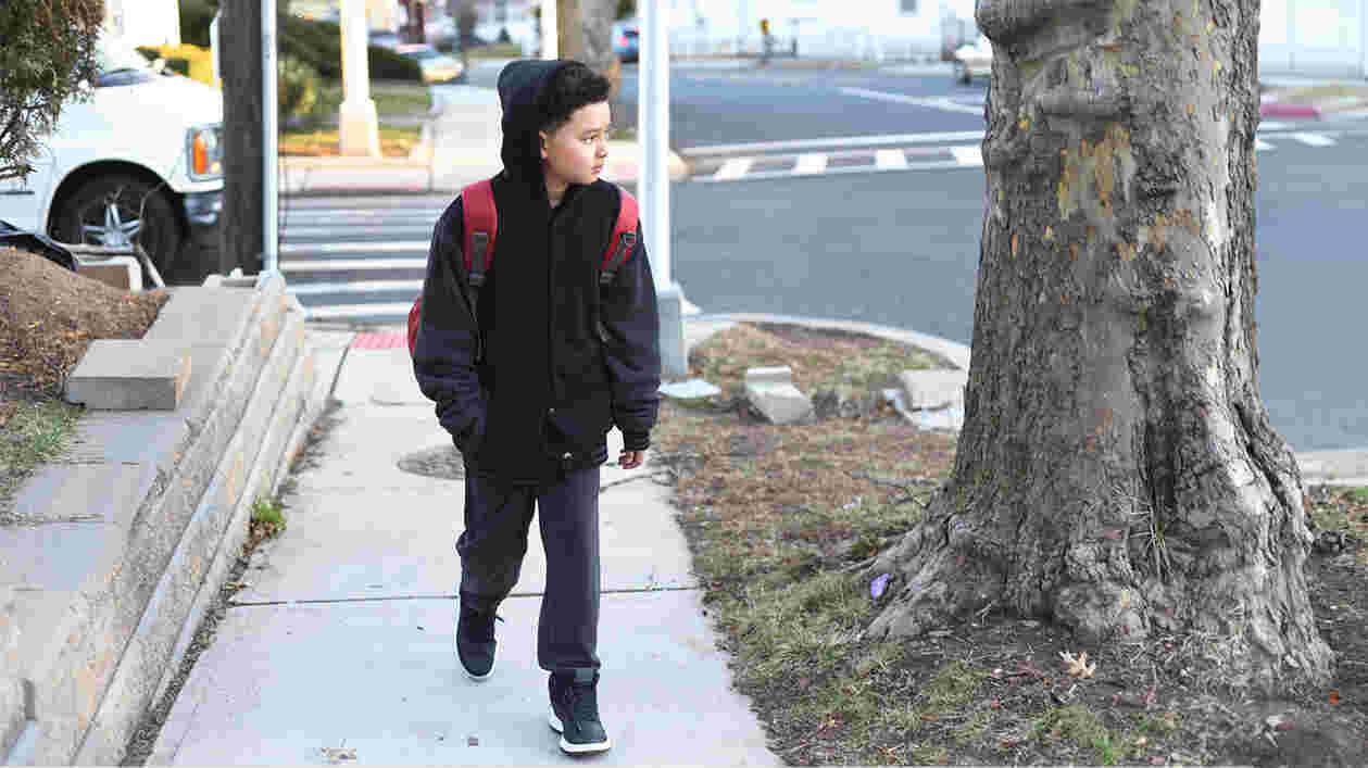 child walks down street with backpack