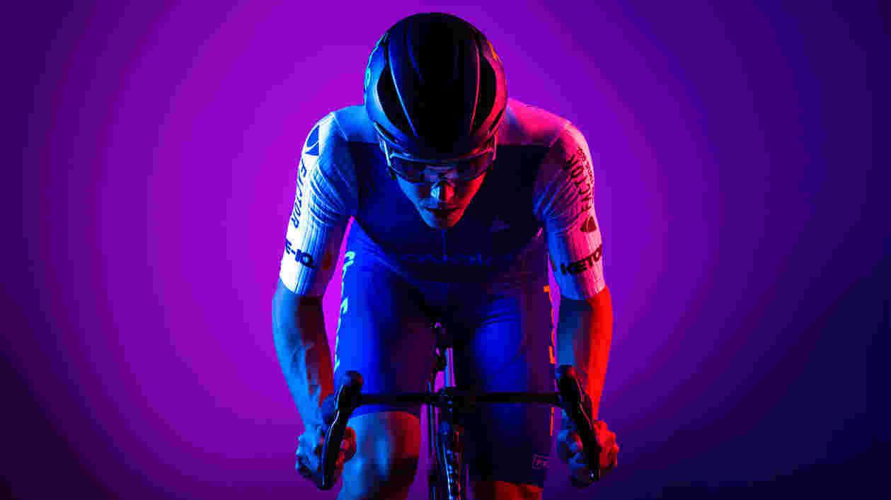 Ryan Collins poses on bike, with purple background