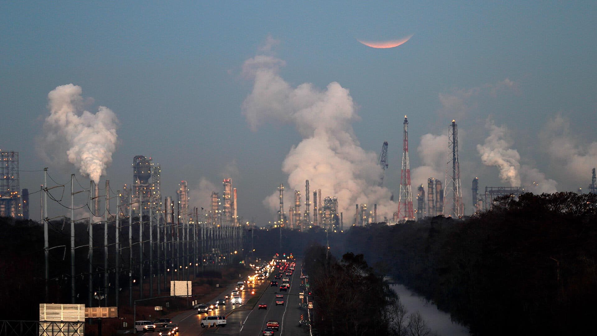 moon rises over oil refineries