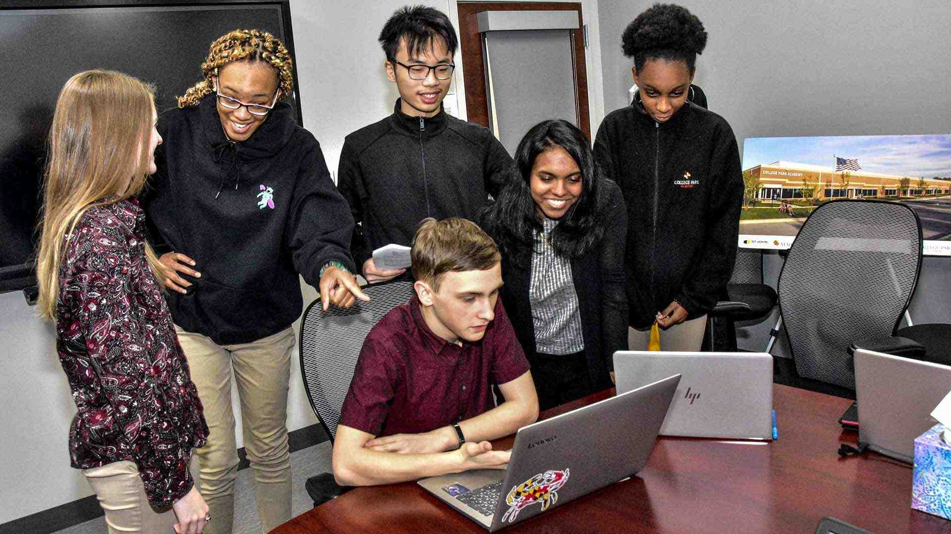 students gather around laptop
