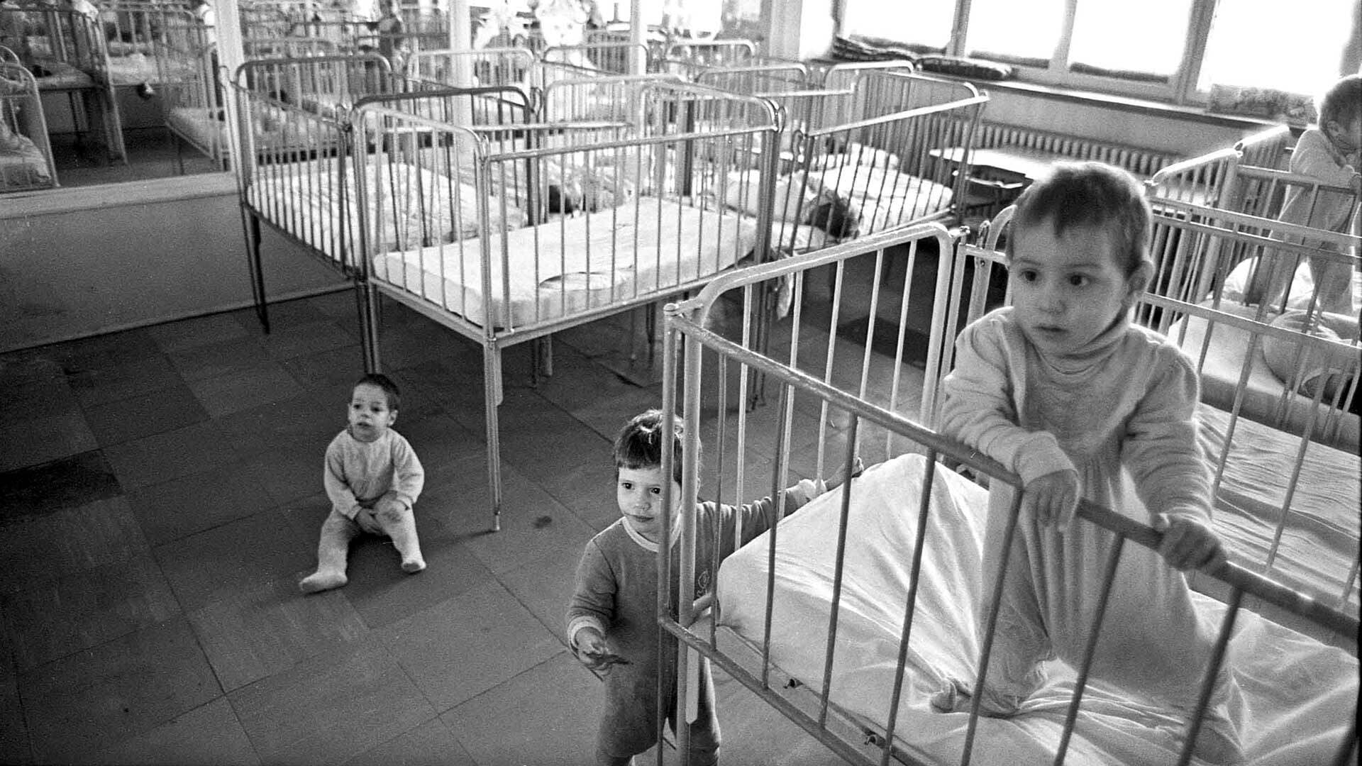 Black and white photo of babies and cribs in a Romanian orphanage