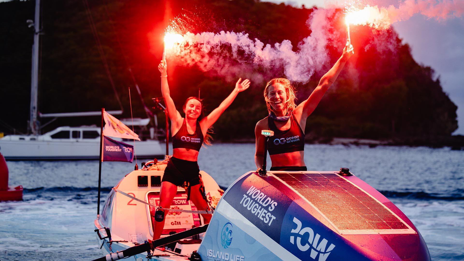Lisa Roland and Nini Champion hold flares at finish line of World's Toughest Row