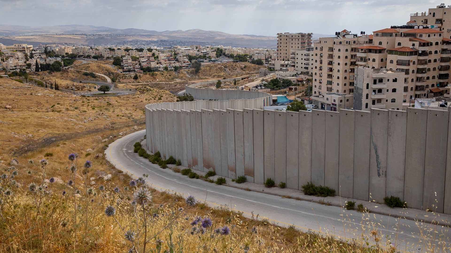 the Shuafat refugee camp is seen behind a section of Israel's separation barrier in Jerusalem
