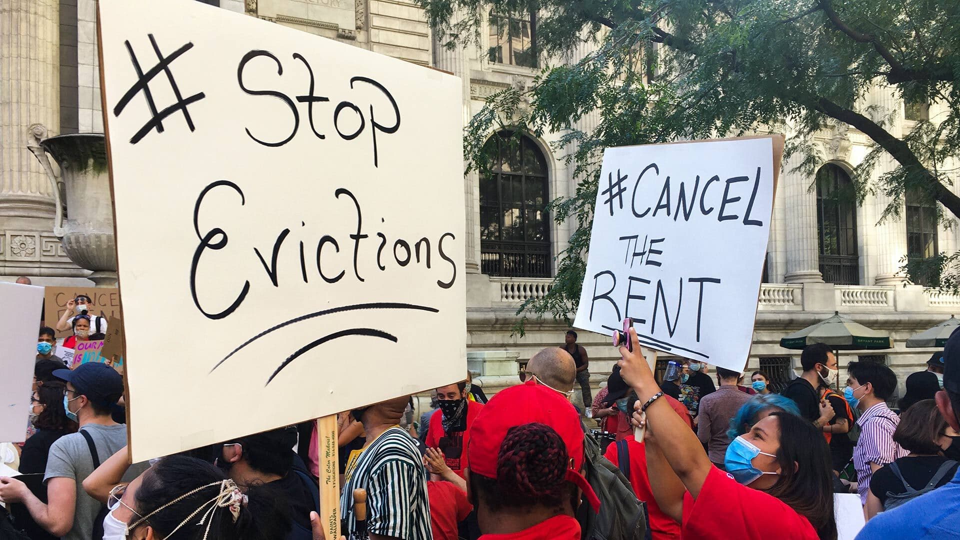 Protesters with signs that read "stop evictions" and "cancel the rent"
