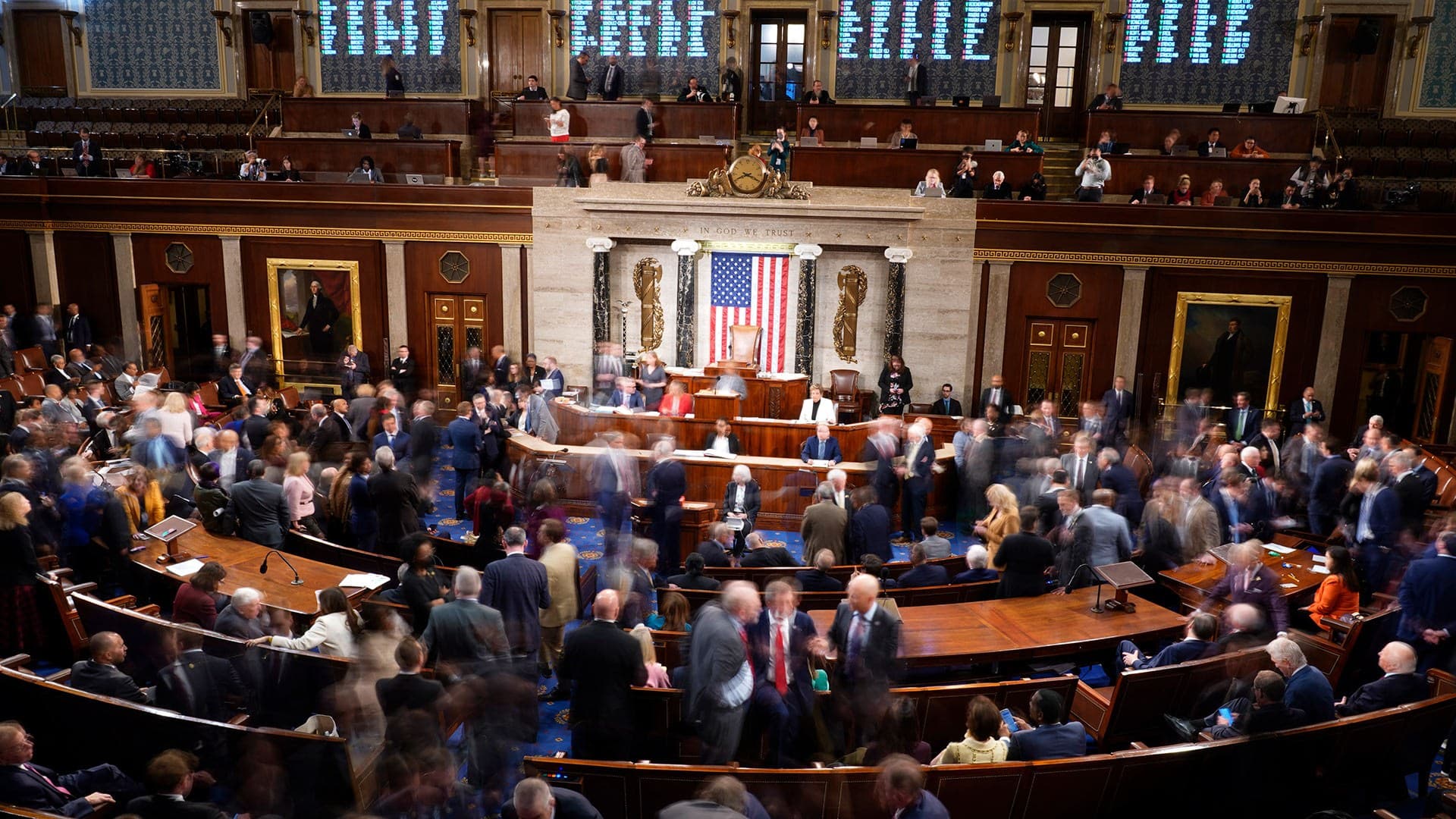 Members walk on the House floor in the House chamber during a roll call vote