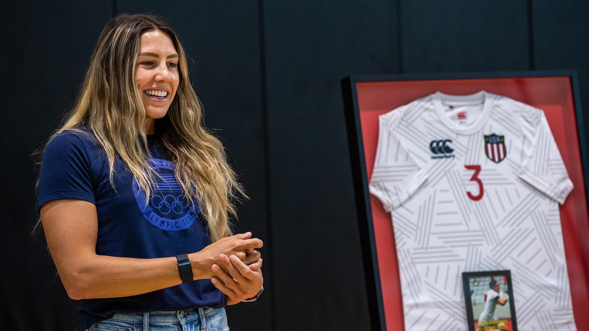 Abby Gustaitis stands next to framed Team USA rugby jersey