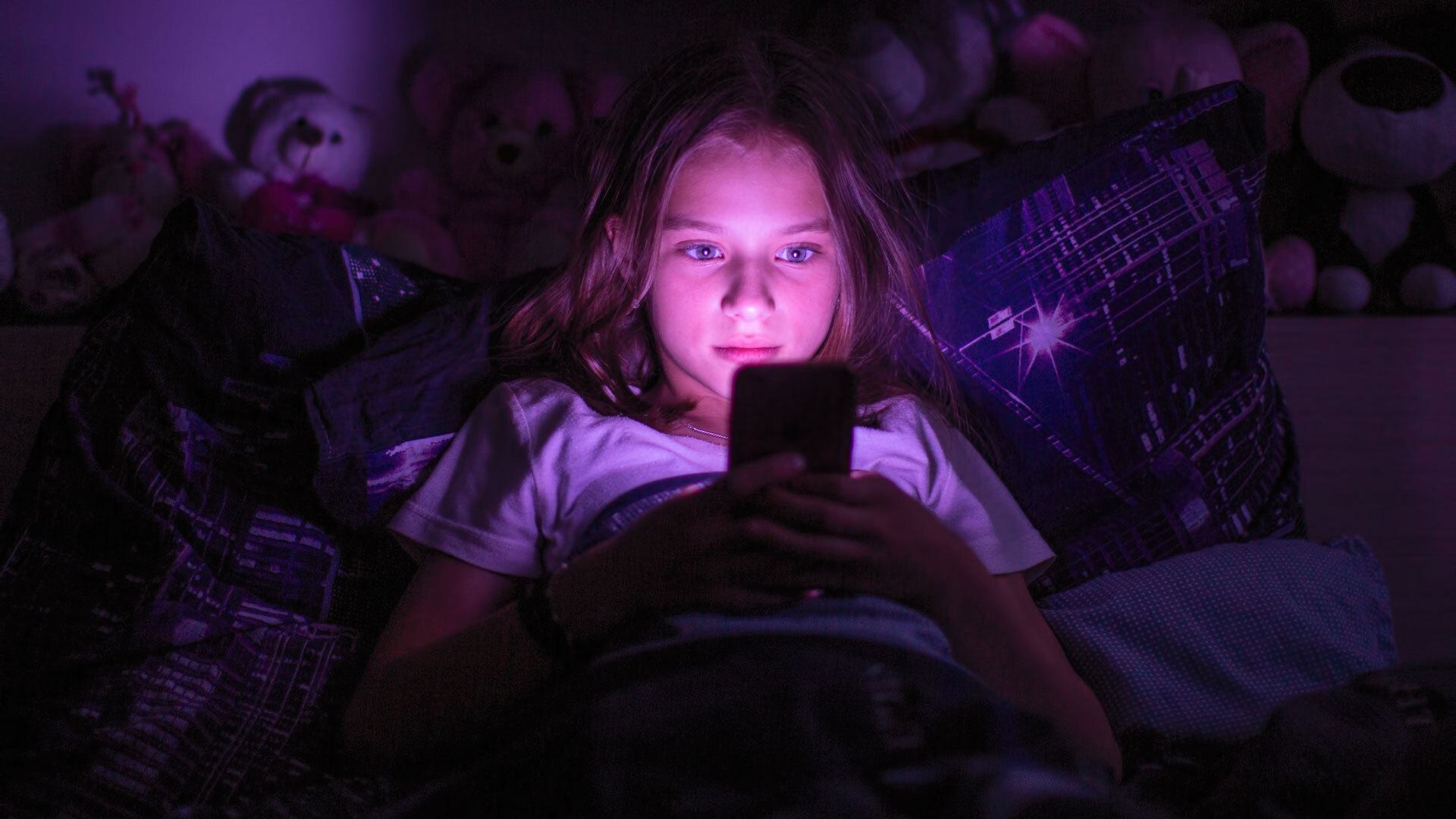 child scrolls on phone in bed