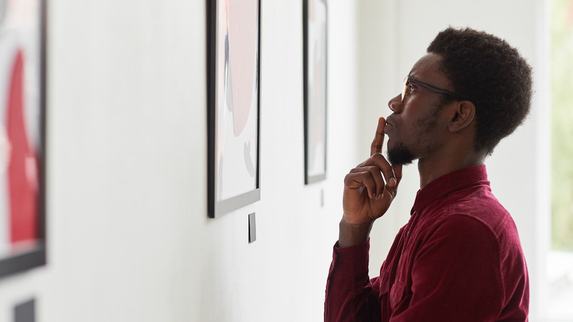 man looks at painting on wall