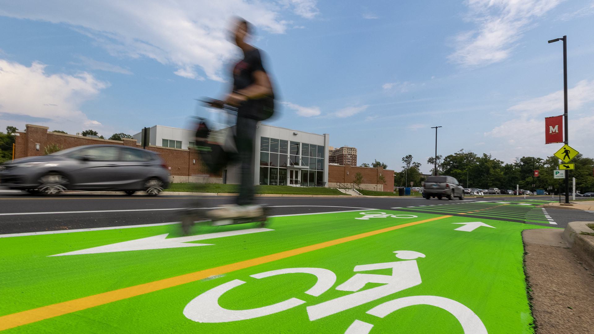 cars and scooters driving by on green bike lanes