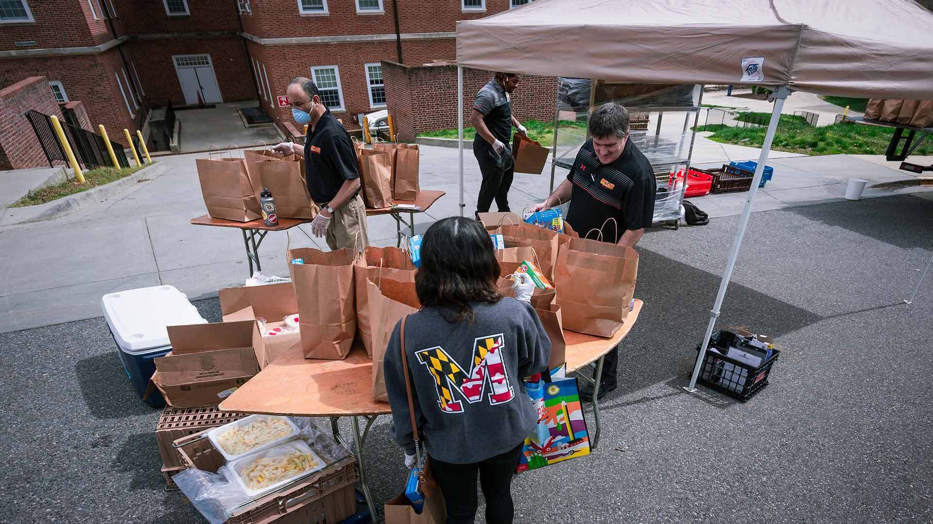 Campus Pantry workers give out bags of food at a tent