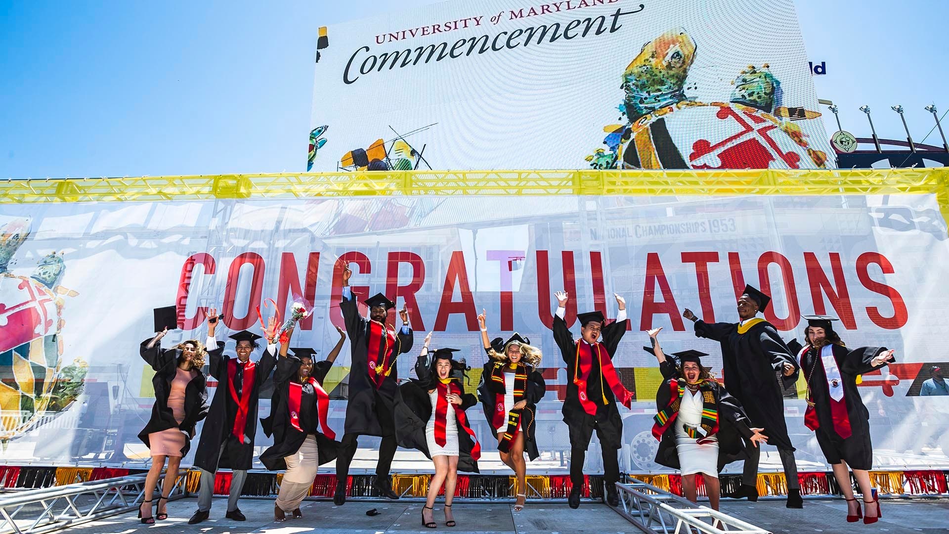 Graduates jumping in front of "Congratulations" sign