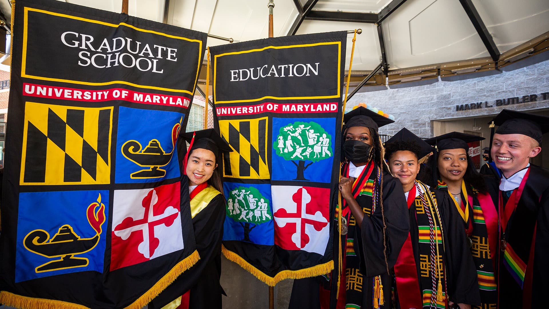 Senior marshals line up and hold gonfalons for the graduate school and college of education at commencement May 2021