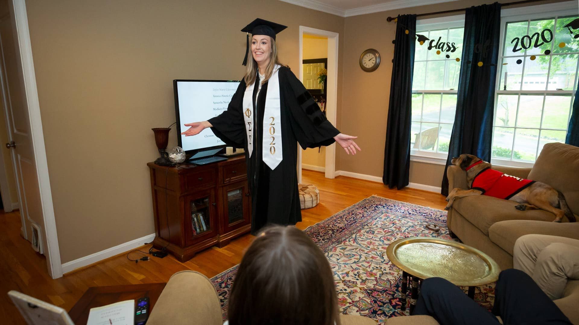 Her family's Silver Spring, Md., living room serves as a virtual stage as Lindsey Collins '20 receives her bachelor of arts in journalism today. Afterward, she and her dog, Leo, share a high-five.