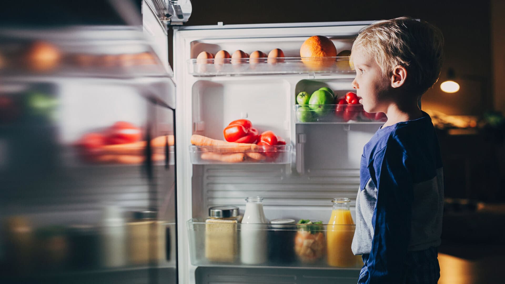 Boy standing at open fridge