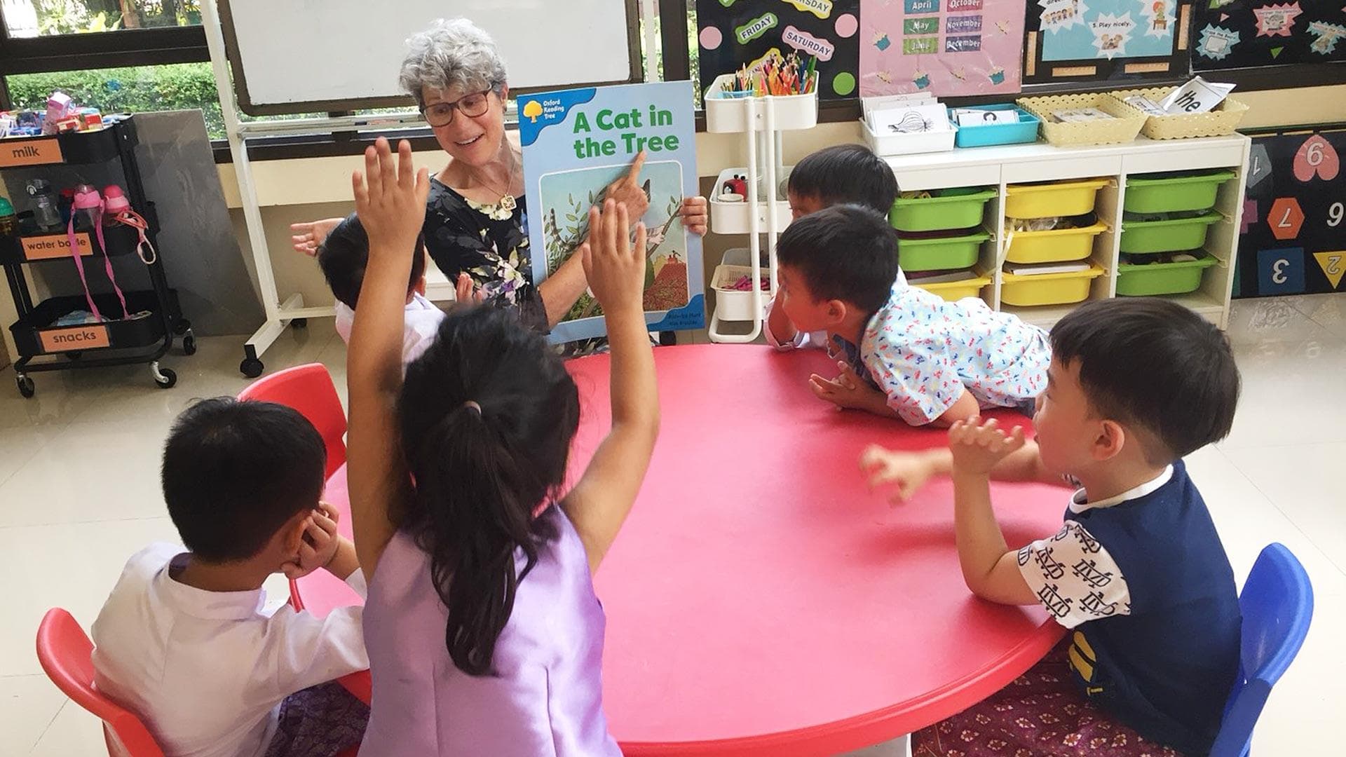 Dian Seidel points to the words "A Cat in the Tree" as kindergarteners watch in a classroom