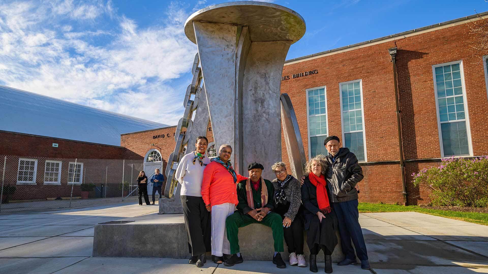 people pose with big sculpture
