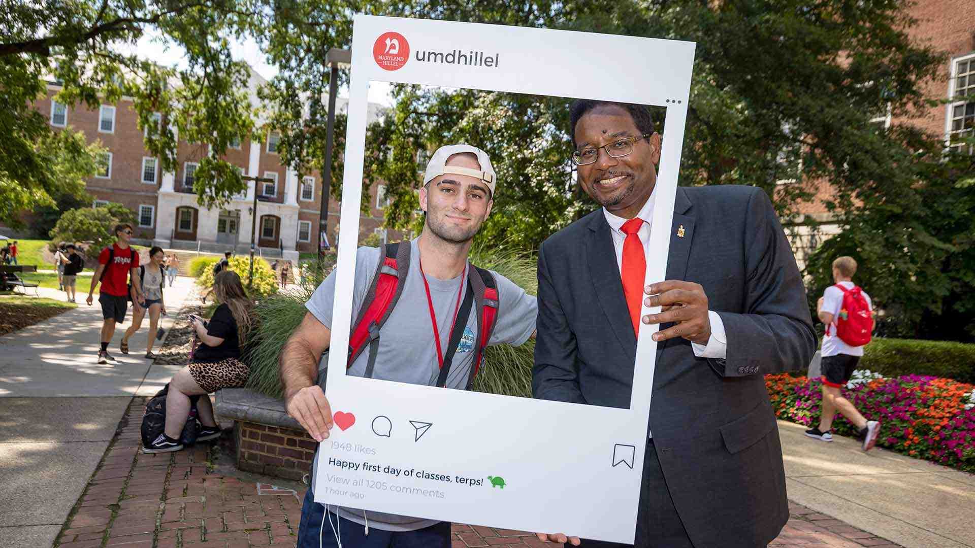 Pines poses with student in frame that says, "umdhillel: Happy first day of classes, Terps!"