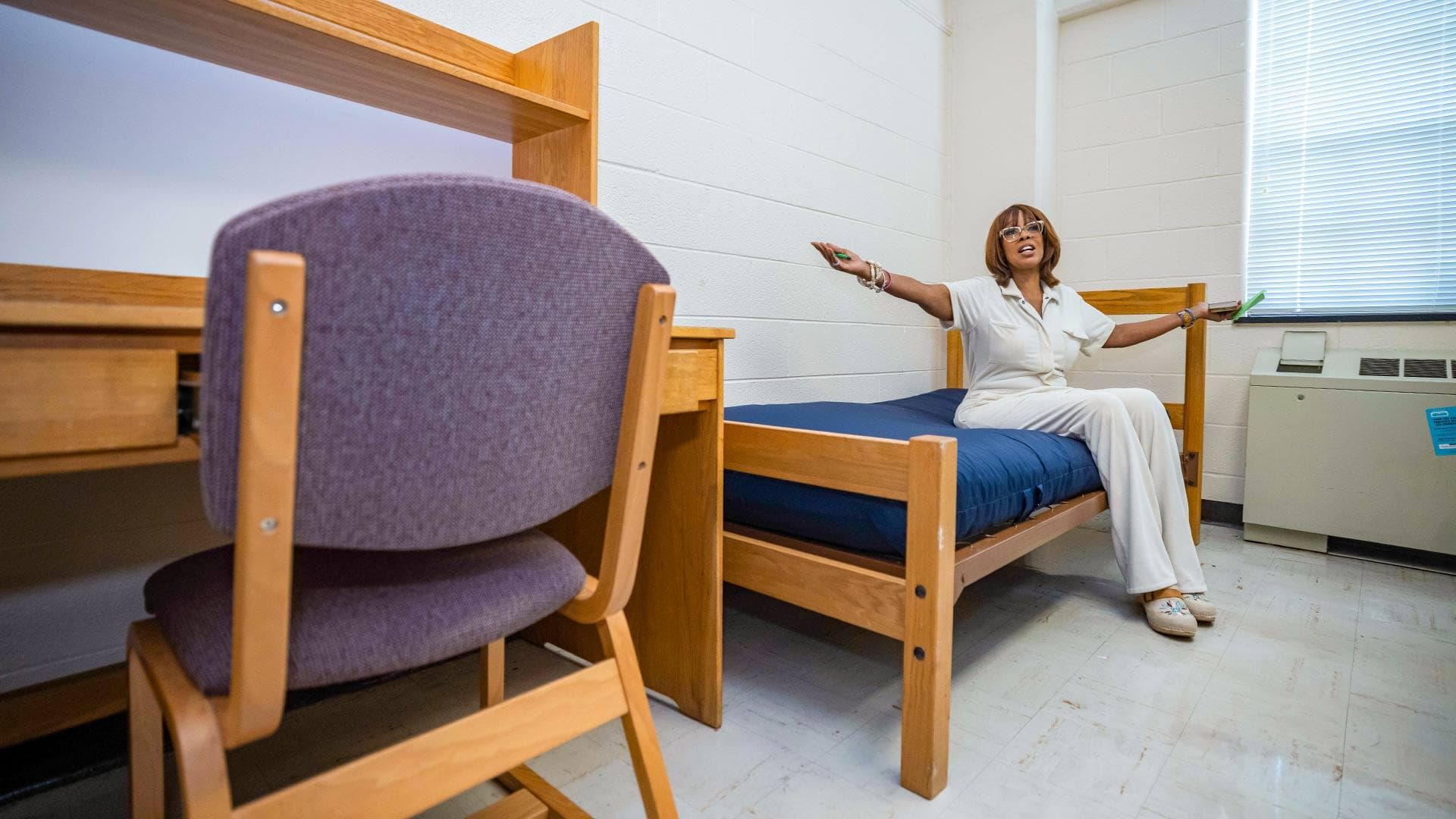 Gayle King sits on a bed in a residence hall