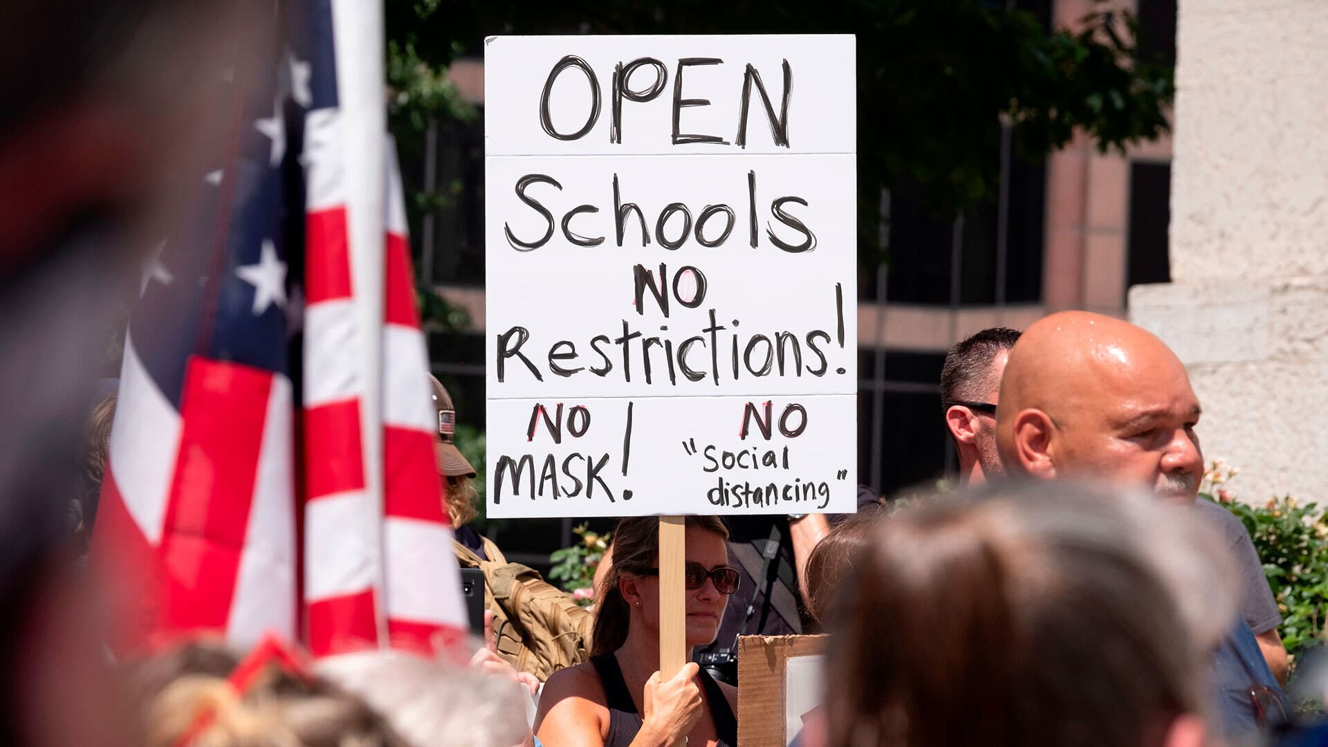 Protesters with sign that reads, "Open schools. No restrictions! No mask! No 'social distancing'"