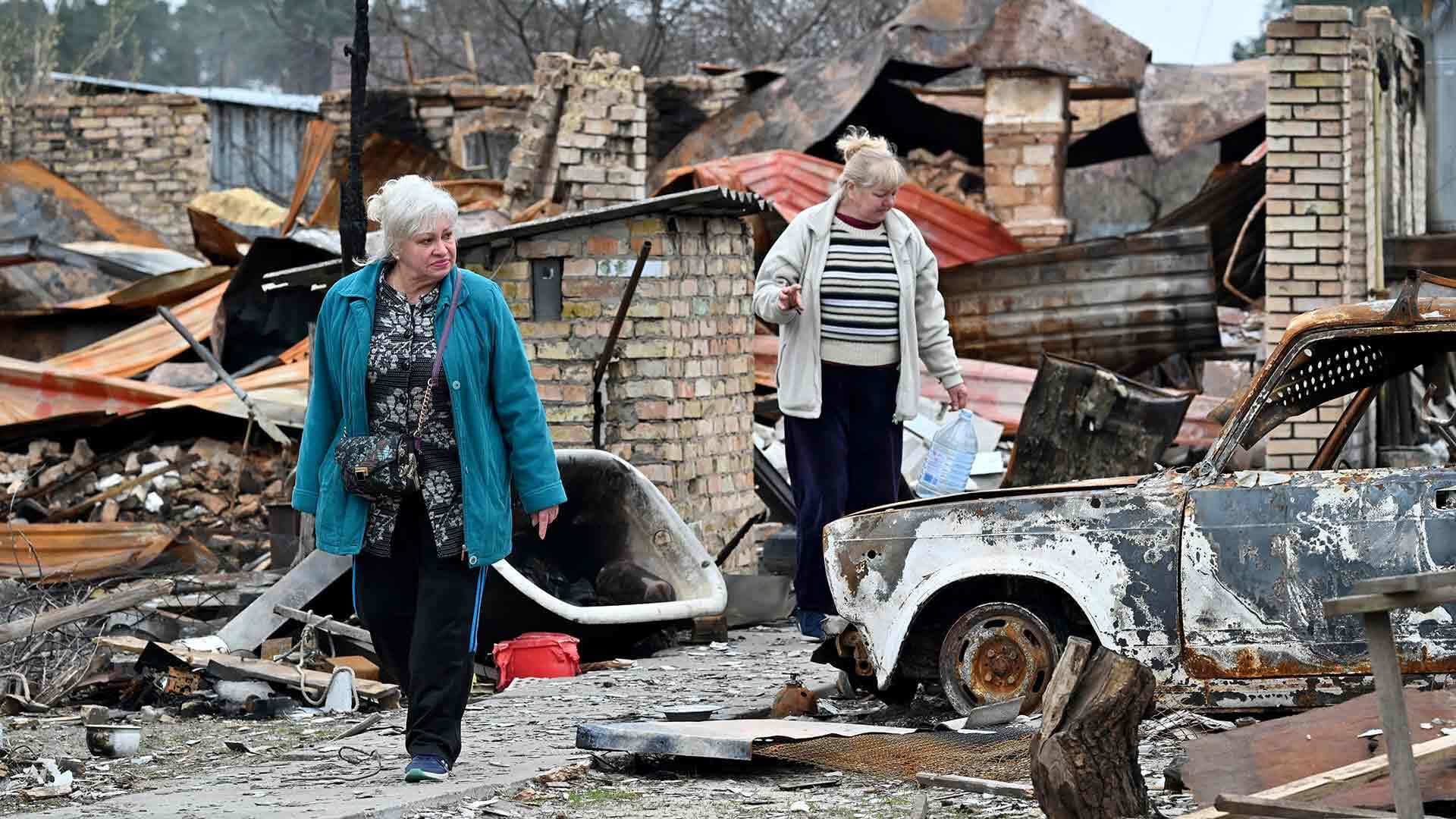 Two women walk amid debris in Kyiv, Ukraine