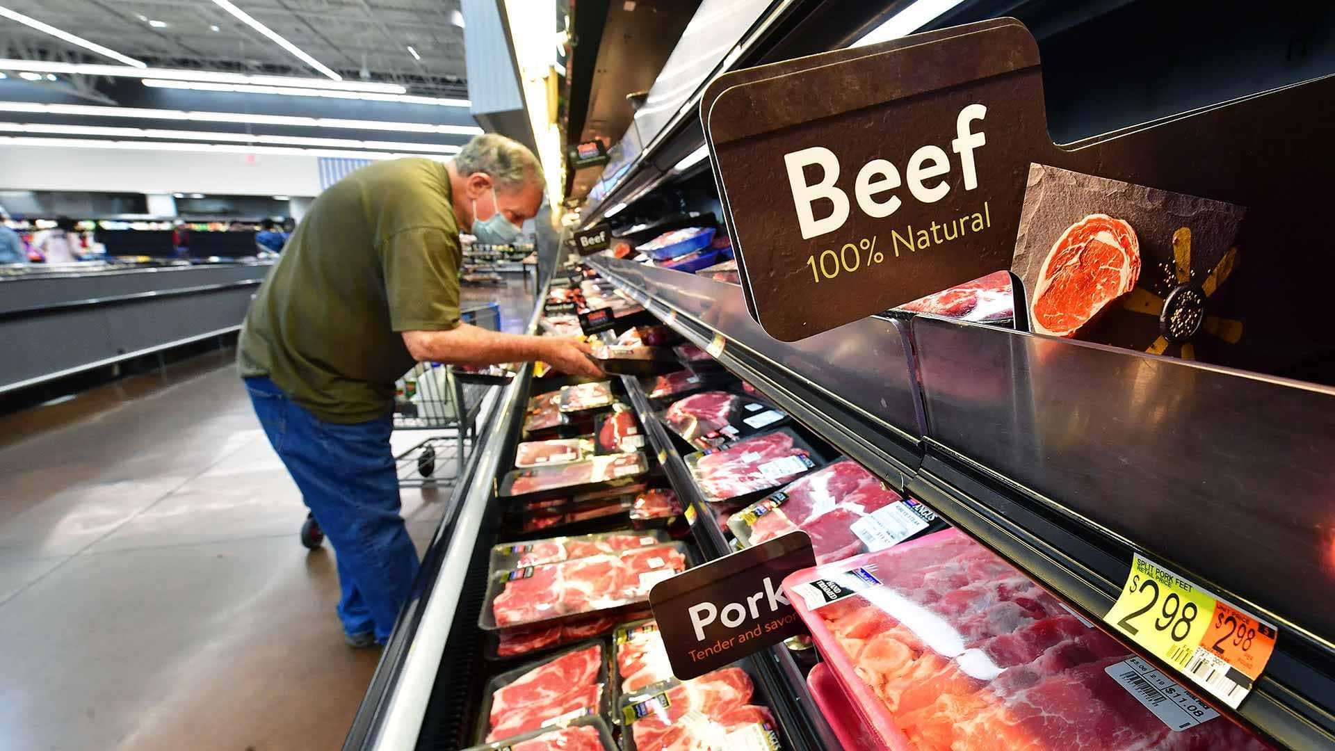 customer shops for meat in section of grocery store