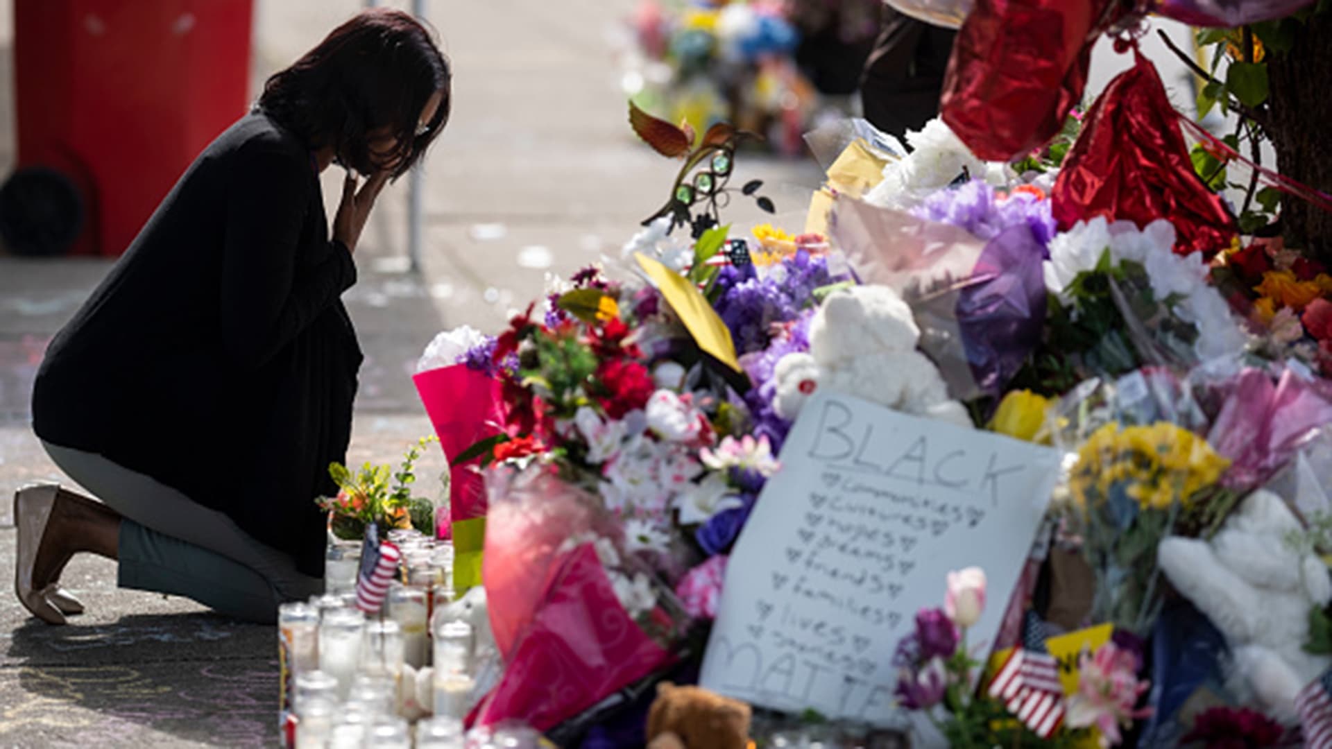 Mourner kneels in front of flowers to pay respects after Buffalo shootings