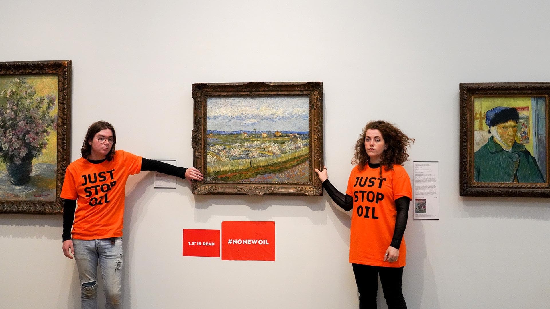 Two people with orange "Just Stop Oil" T-shirts glue their hands to a Van Gogh painting