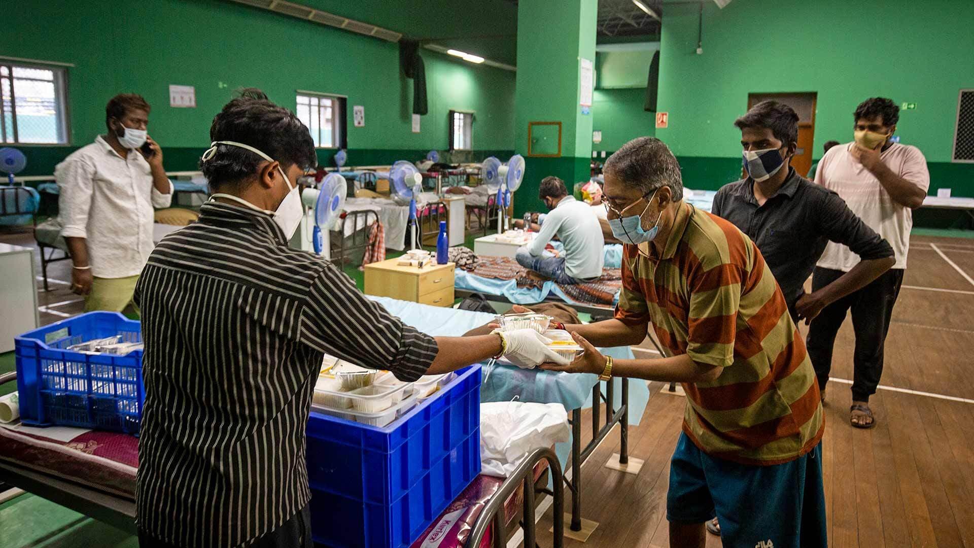 COVID-19 patients receive food at a makeshift hospital in Bengaluru, India