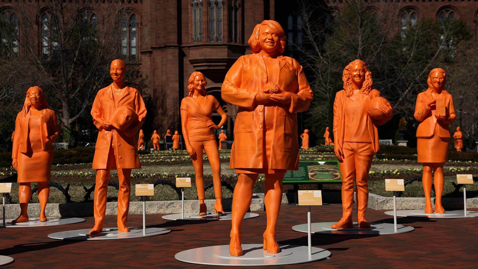 Orange statues, part of “#IfThenSheCan—The Exhibit”