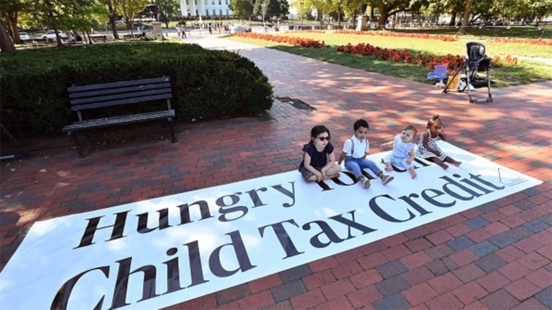 kids sit on sign protesting loss of expanded child tax credit outside White House