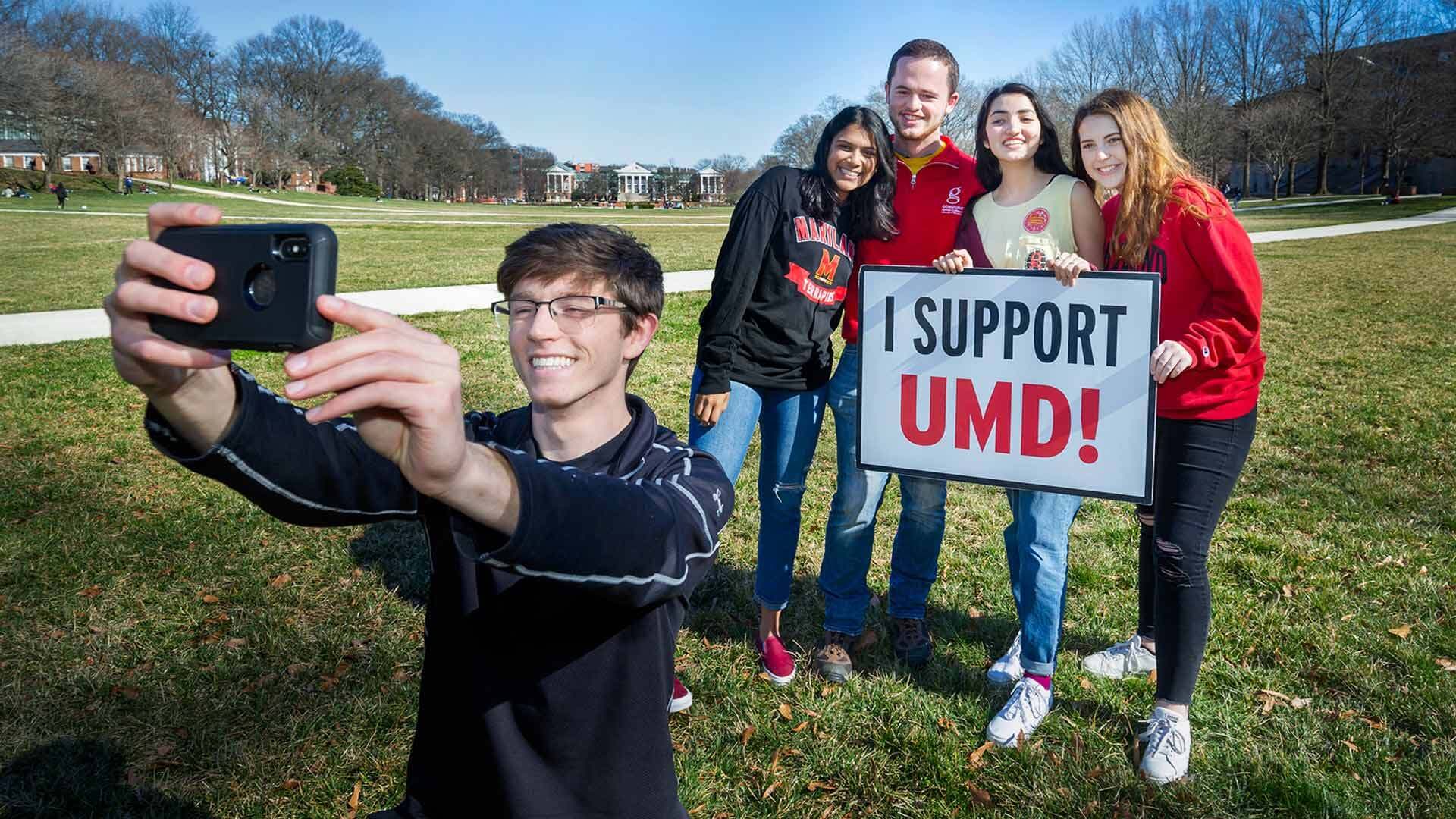 Students take a selfie on Giving Day with sign that reads, "I Support UMD!"