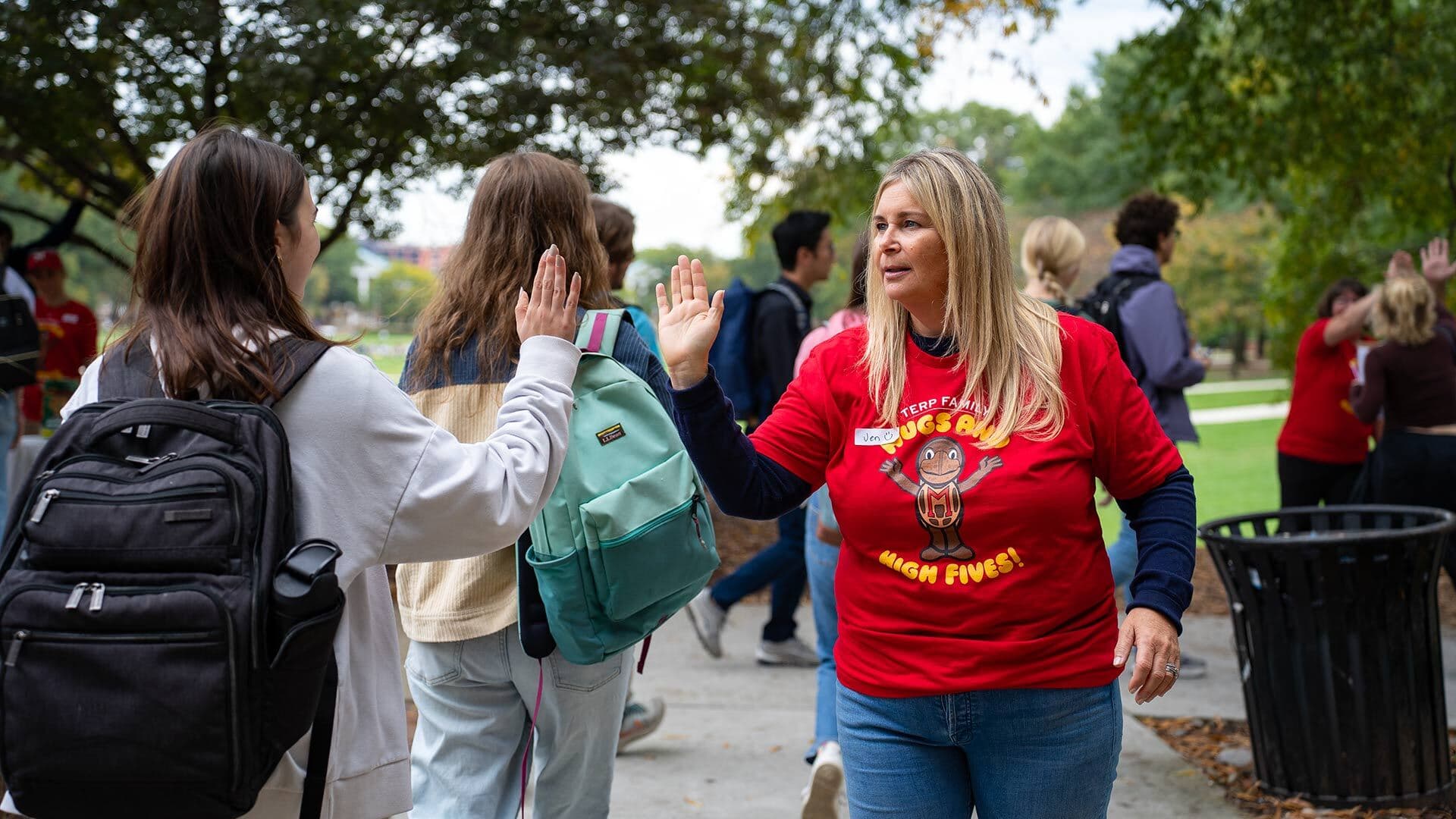 A mom offers a high five to passing students
