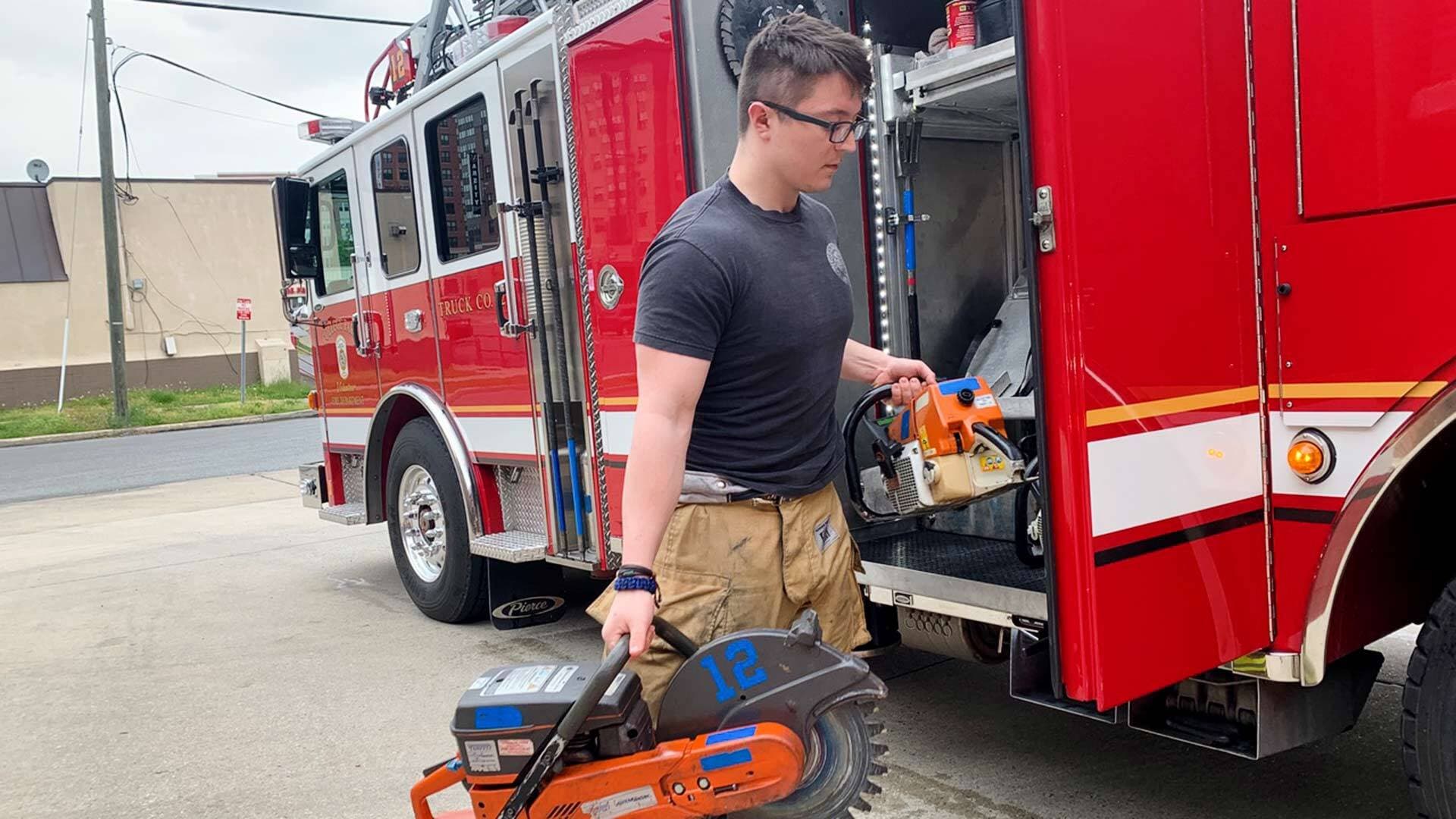 Student volunteer loads equipment onto a firetruck