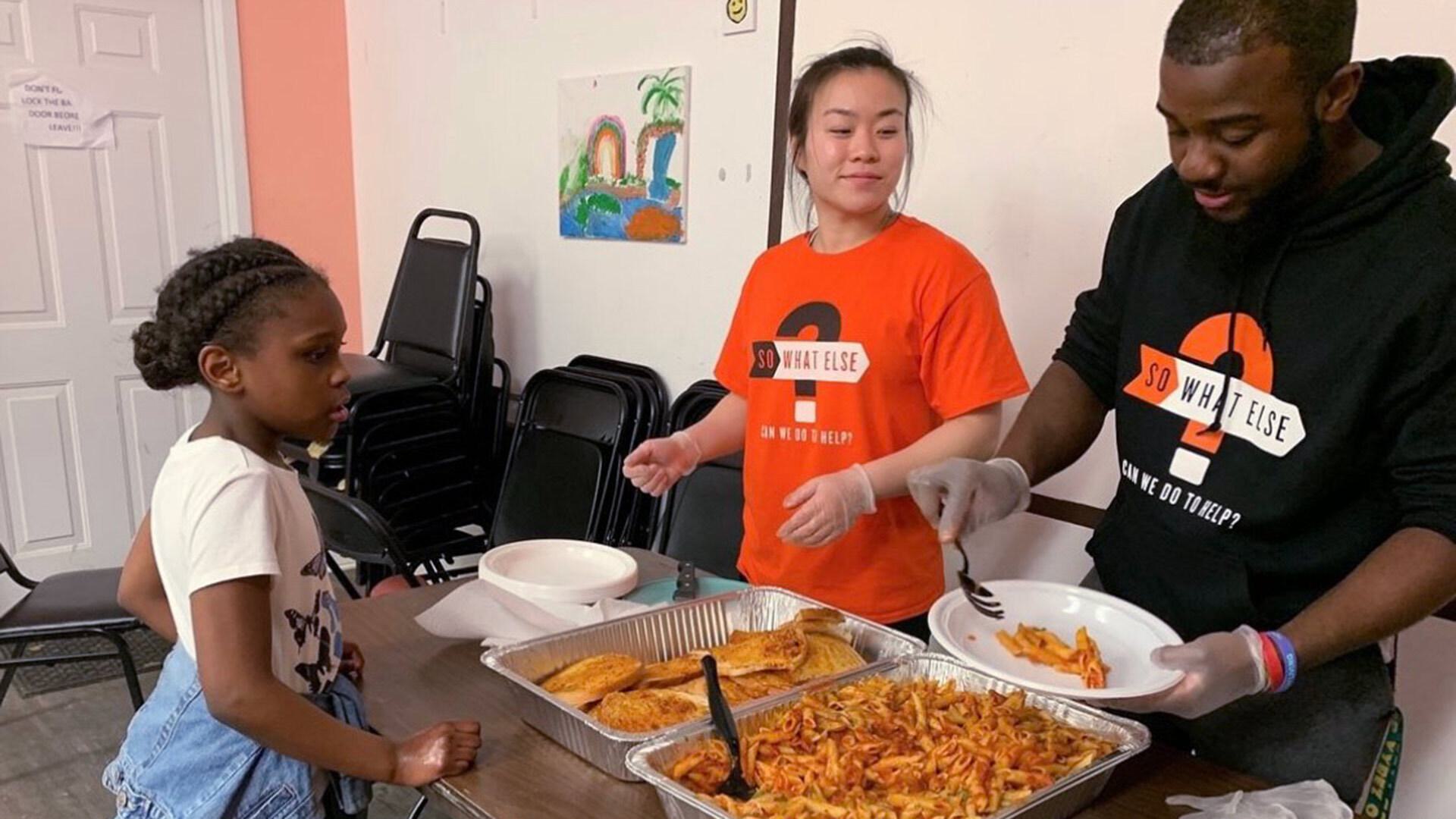 two volunteers serve food to child