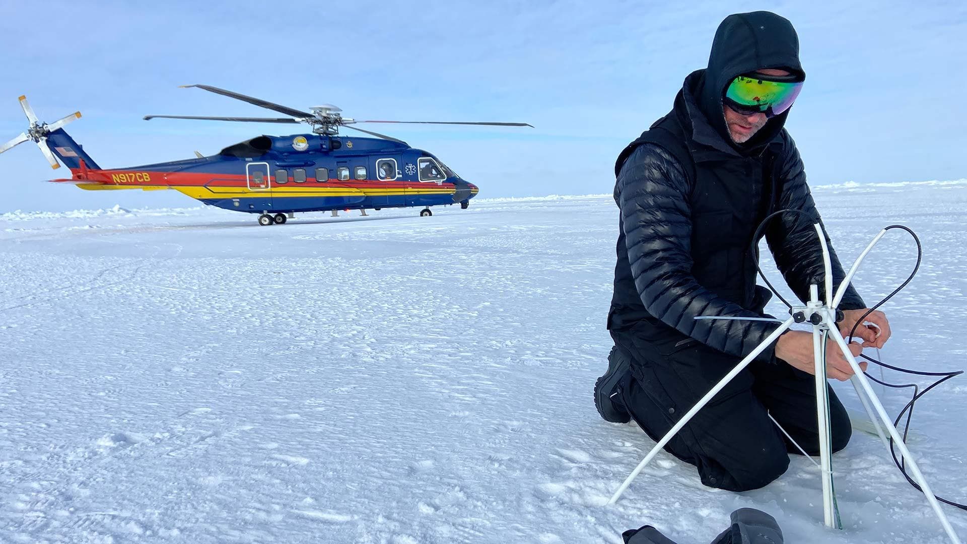 Cy Keener works in Arctic with helicopter in background