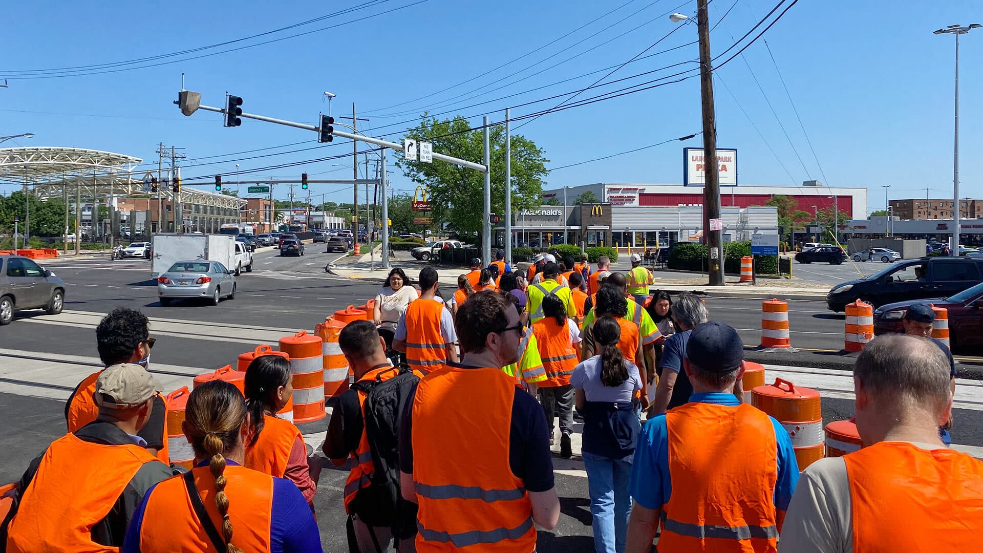 group wearing orange vests crosses street at intersection