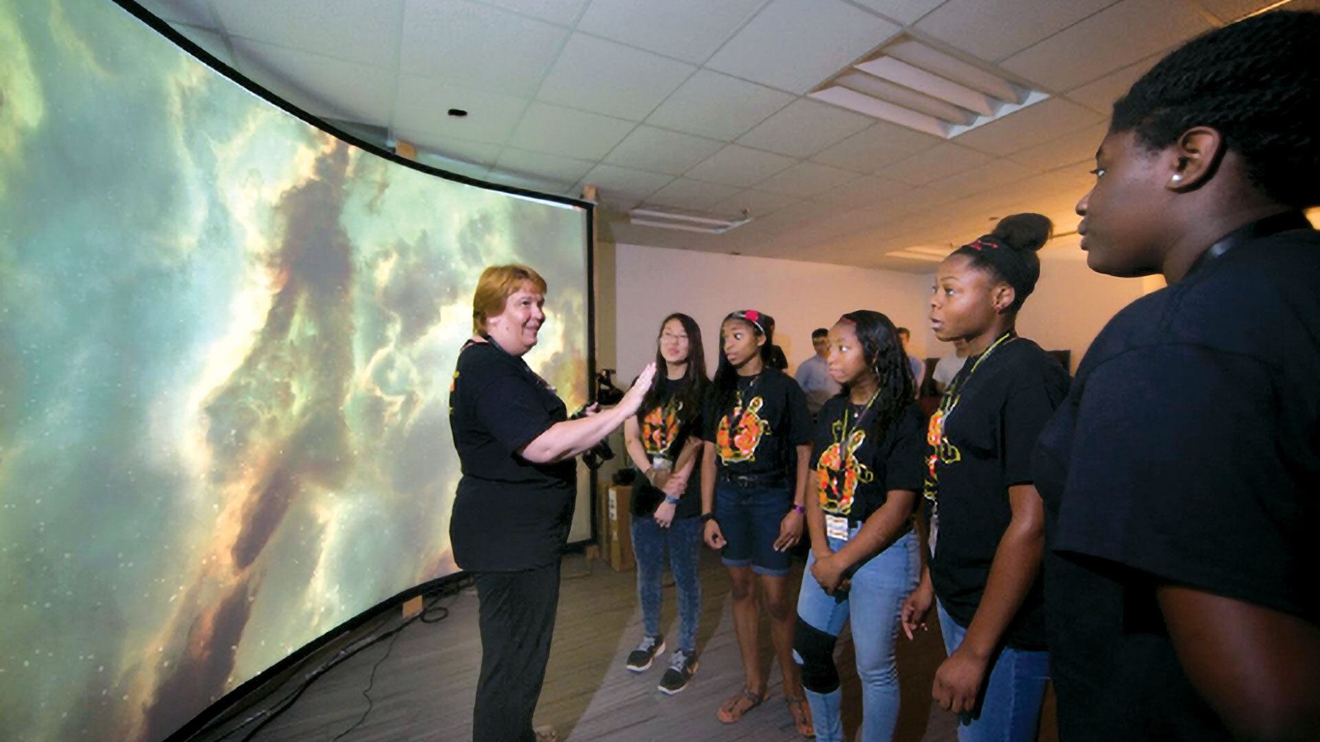 woman speaks to students in front of big screen