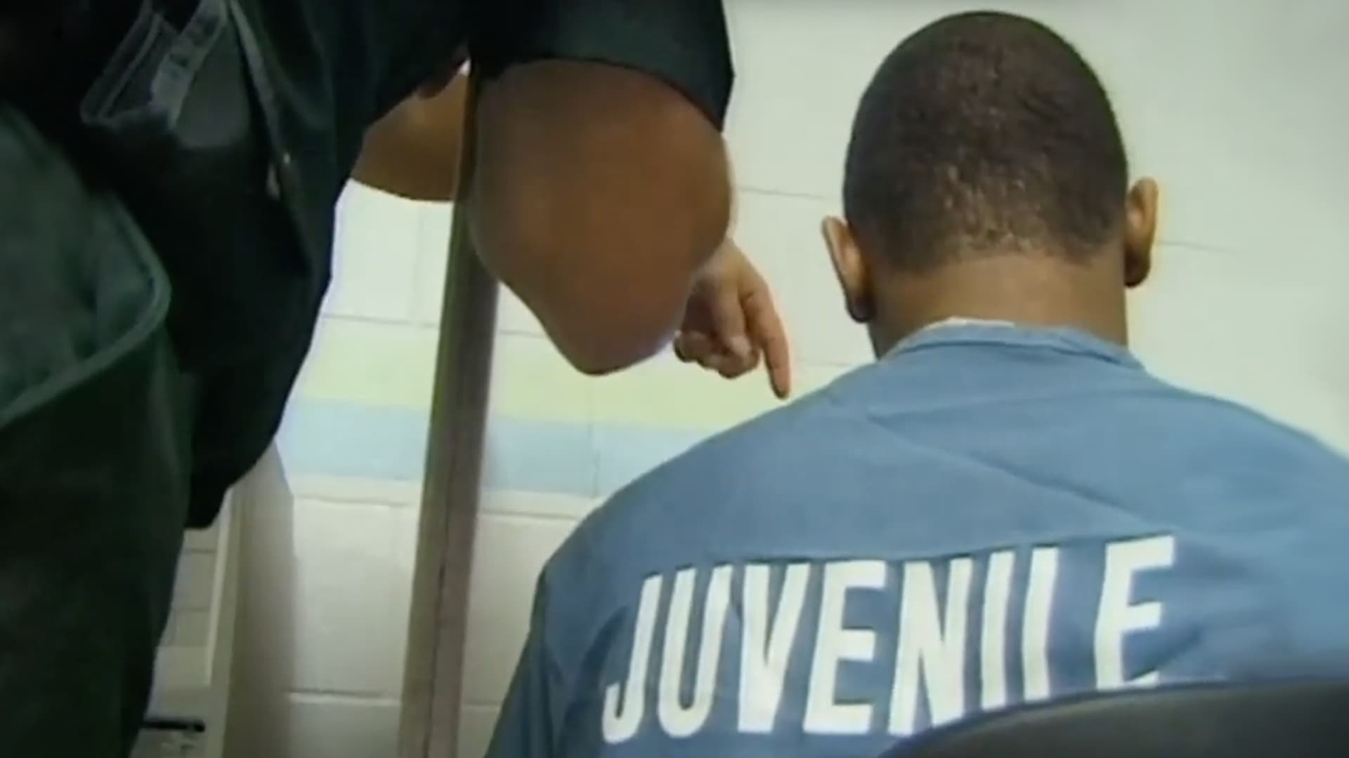 Screengrab of back of prisoner with "juvenile" written on his shirt