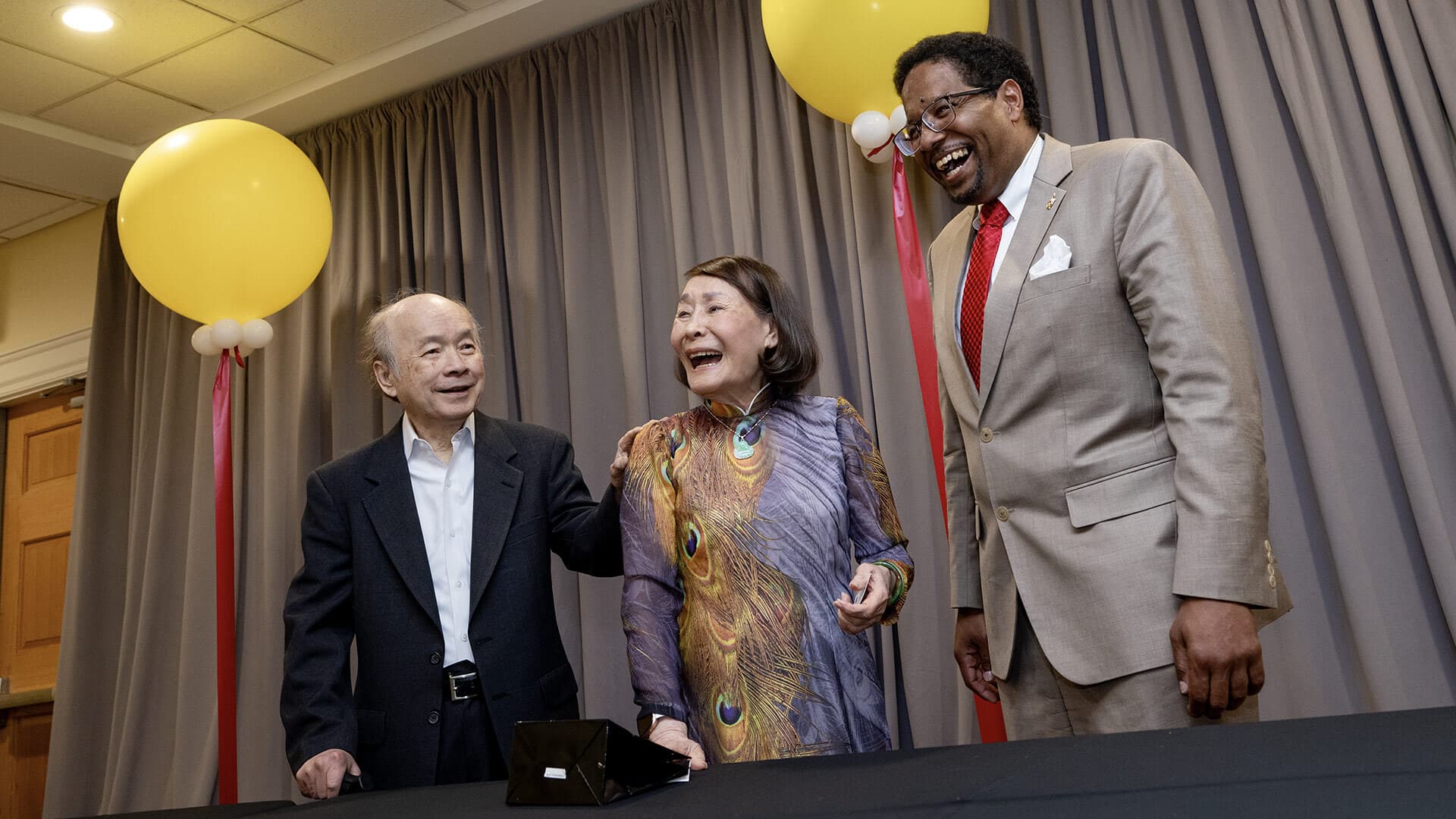 Long Nguyen, Kimmy Duong and Darryll Pines laugh, with two yellow balloons in background