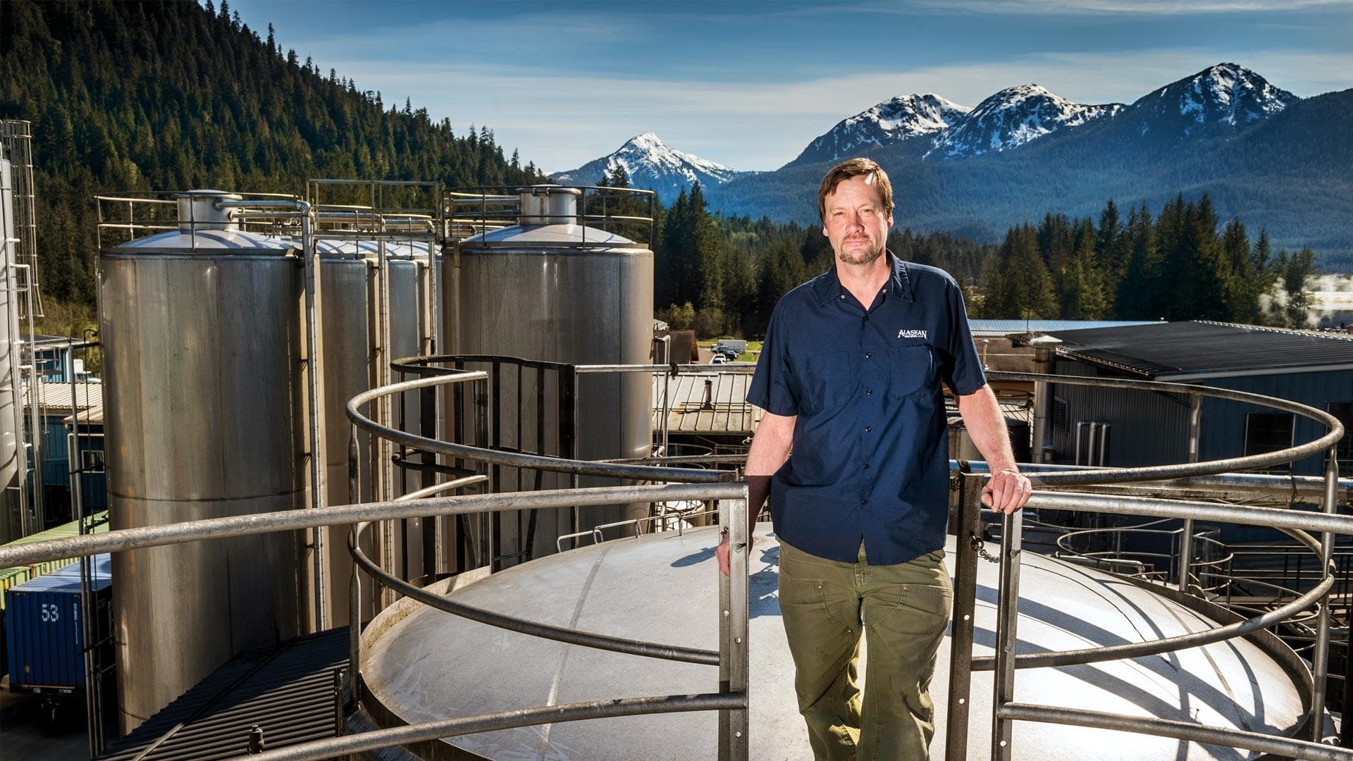 Geoff Larson ’80 stands in front of brewing equipment in Alaska