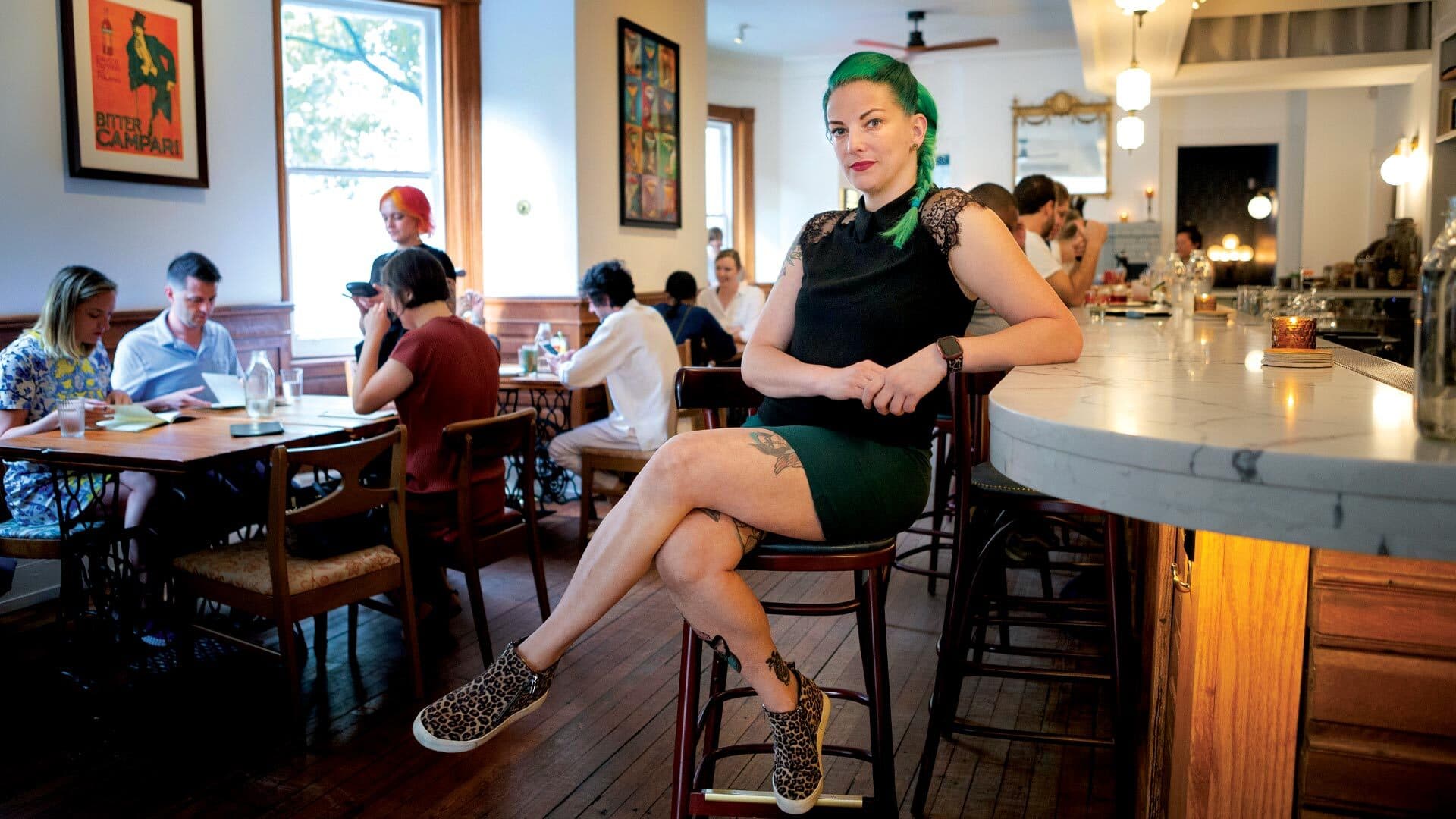 Amie Ward sits at a busy bar with patrons around her