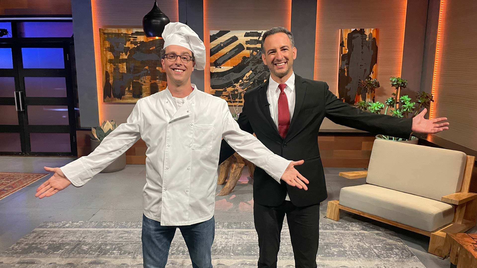 Ethan Frisch, wearing a chef's outfit, poses with Burlap and Barrel co-founder Ori Zohar on "Shark Tank" set