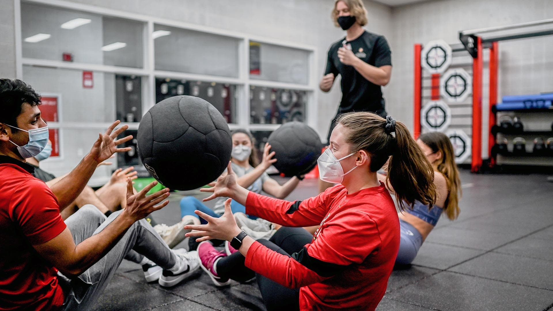 Students throw medicine balls in UMD RecWell group fitness class