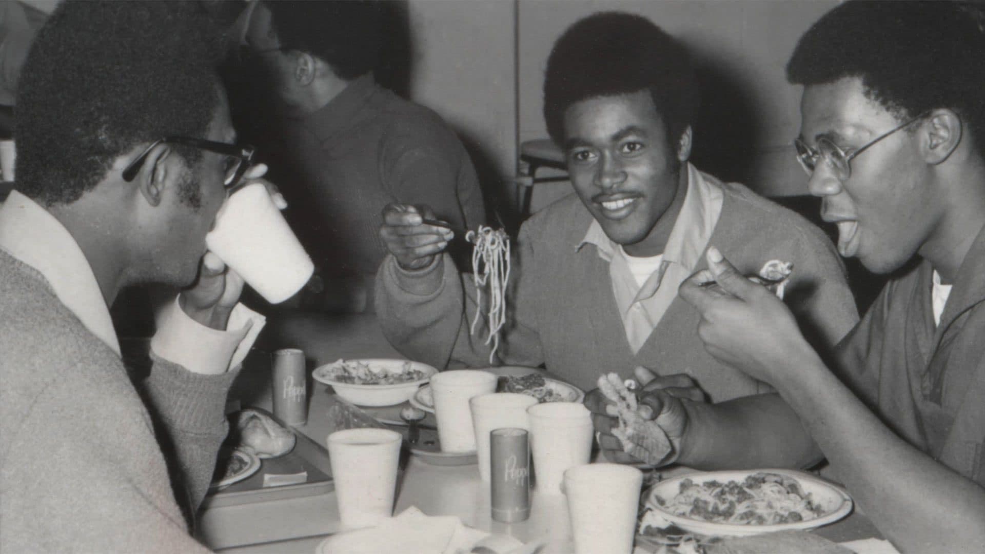 archival photo of students eating spaghetti in the dining hall