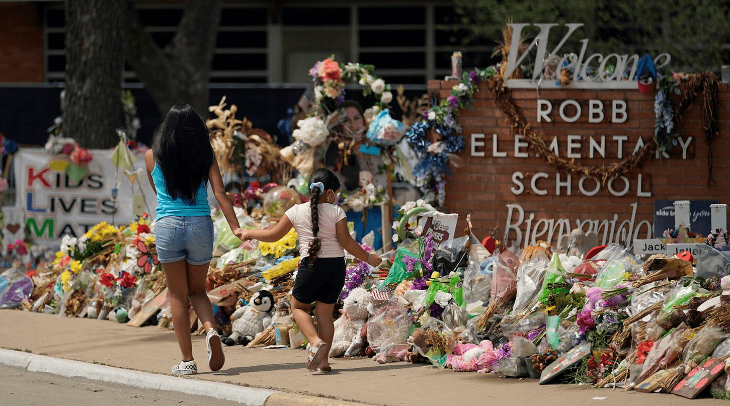 Visitors walk past a makeshift memorial honoring those recently killed at Robb Elementary School, Tuesday, July 12, 2022, in Uvalde, Texas.