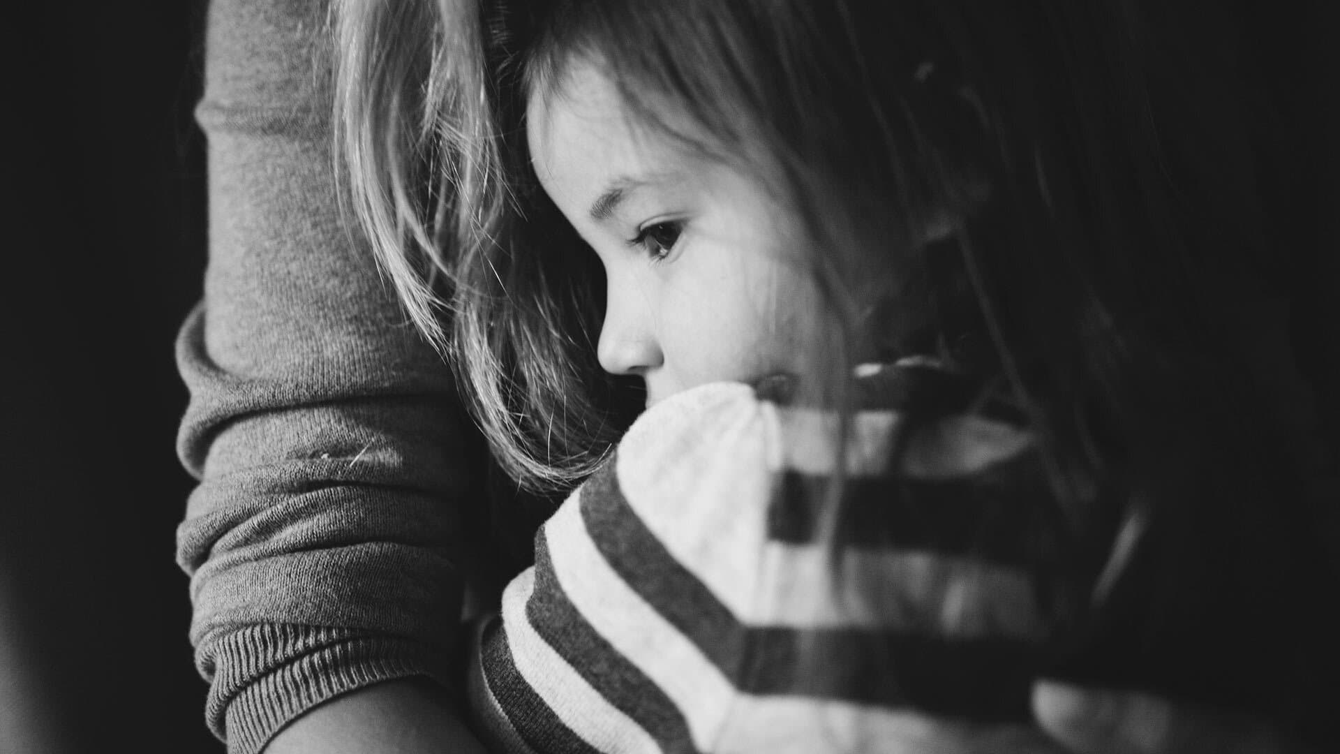 Black and white close-up photo of young girl hugging mother
